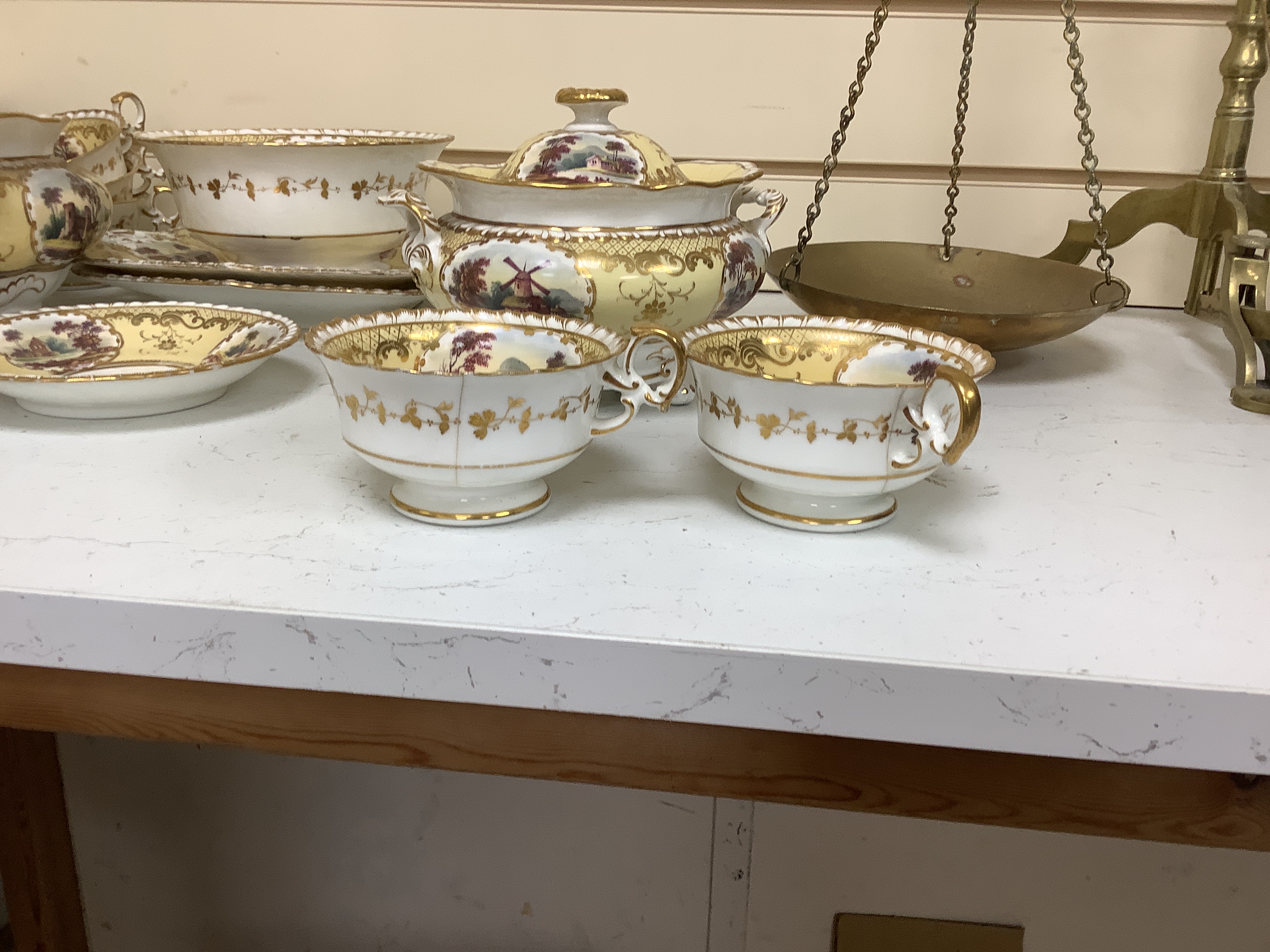 An English porcelain tea set, c.1835-45, including a teapot and cover, sucrier and cover, slops bowl, milk jug, teacups and saucers, two cake plates, each piece painted with buildings in landscapes, yellow ground, patter